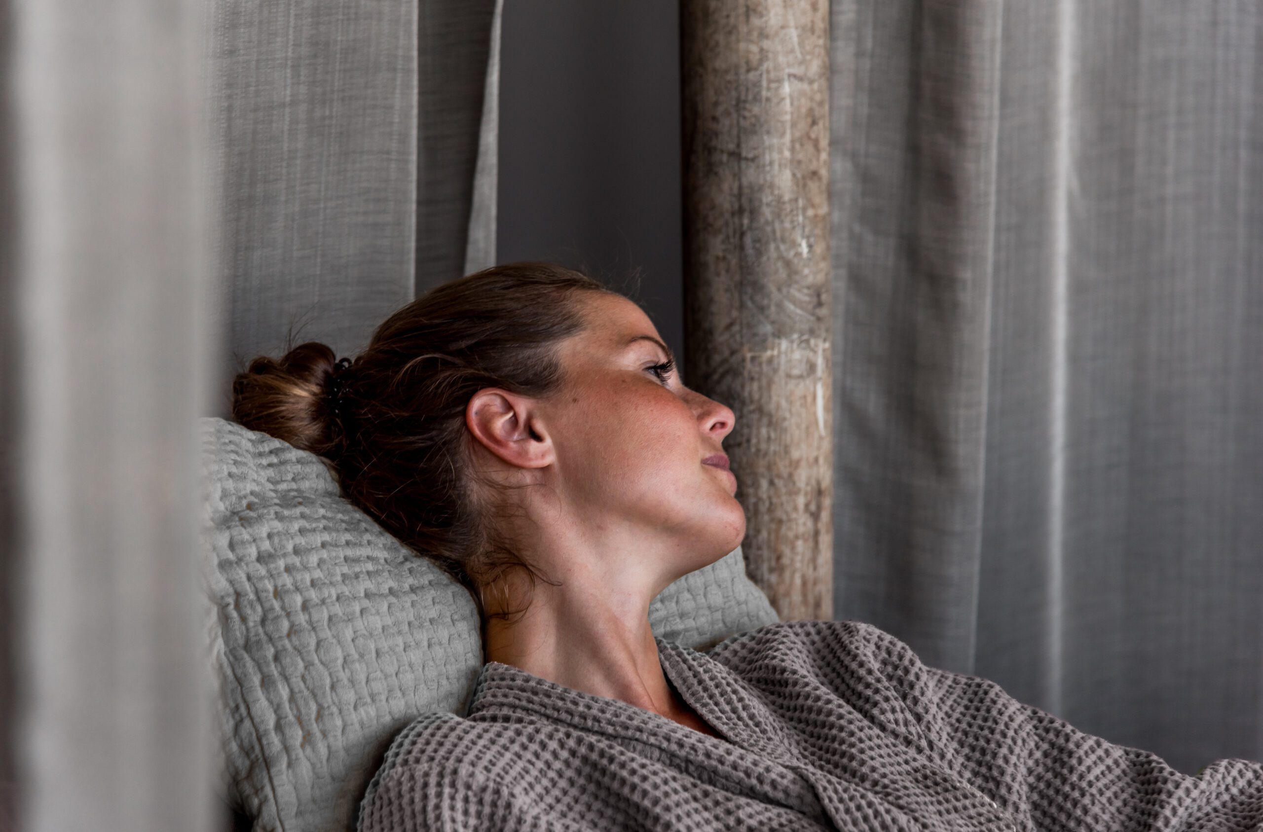 A woman is lying in a recliner wearing a bathrobe.