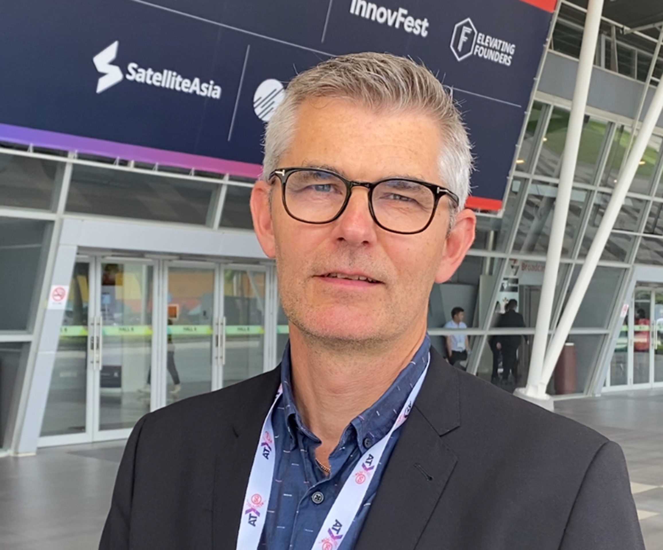 A man in a suit in front of a large sign that says Innovfest and SatelliteAsia