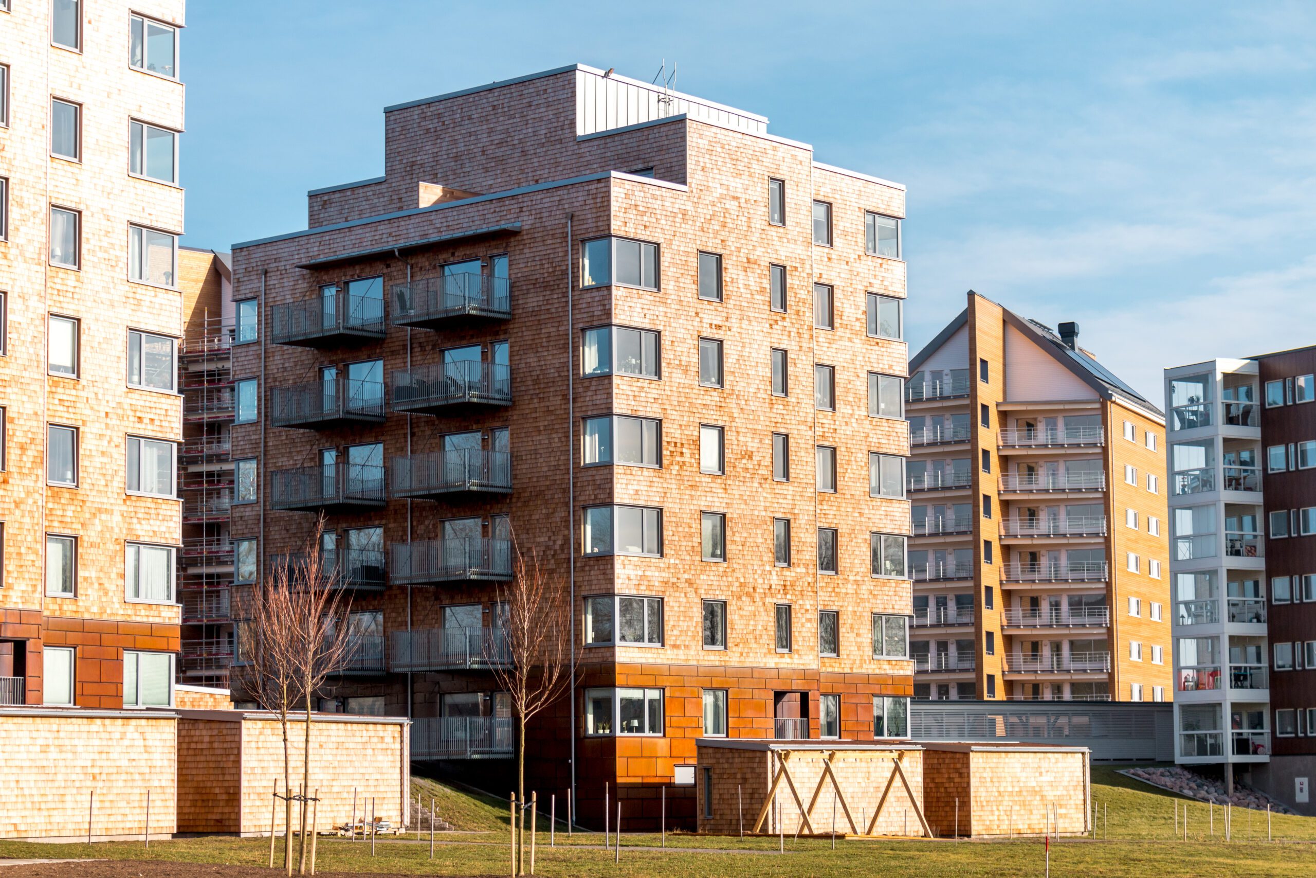 Ett lägenhetshus i tegel med stora glasfönster och balkonger i glas.