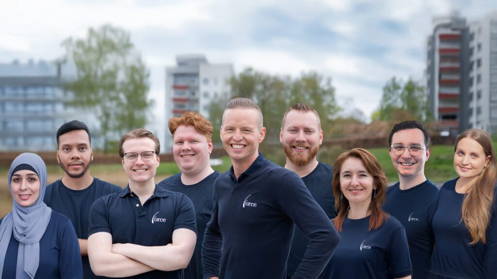 En grupp människor står ute med träd bakom. De är arbetskollegor på företaget Force HT i Skövde